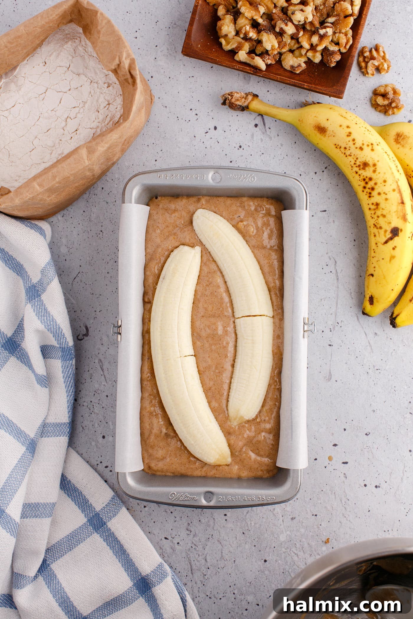 banana slice placed on top of banana bread batter in a loaf pan