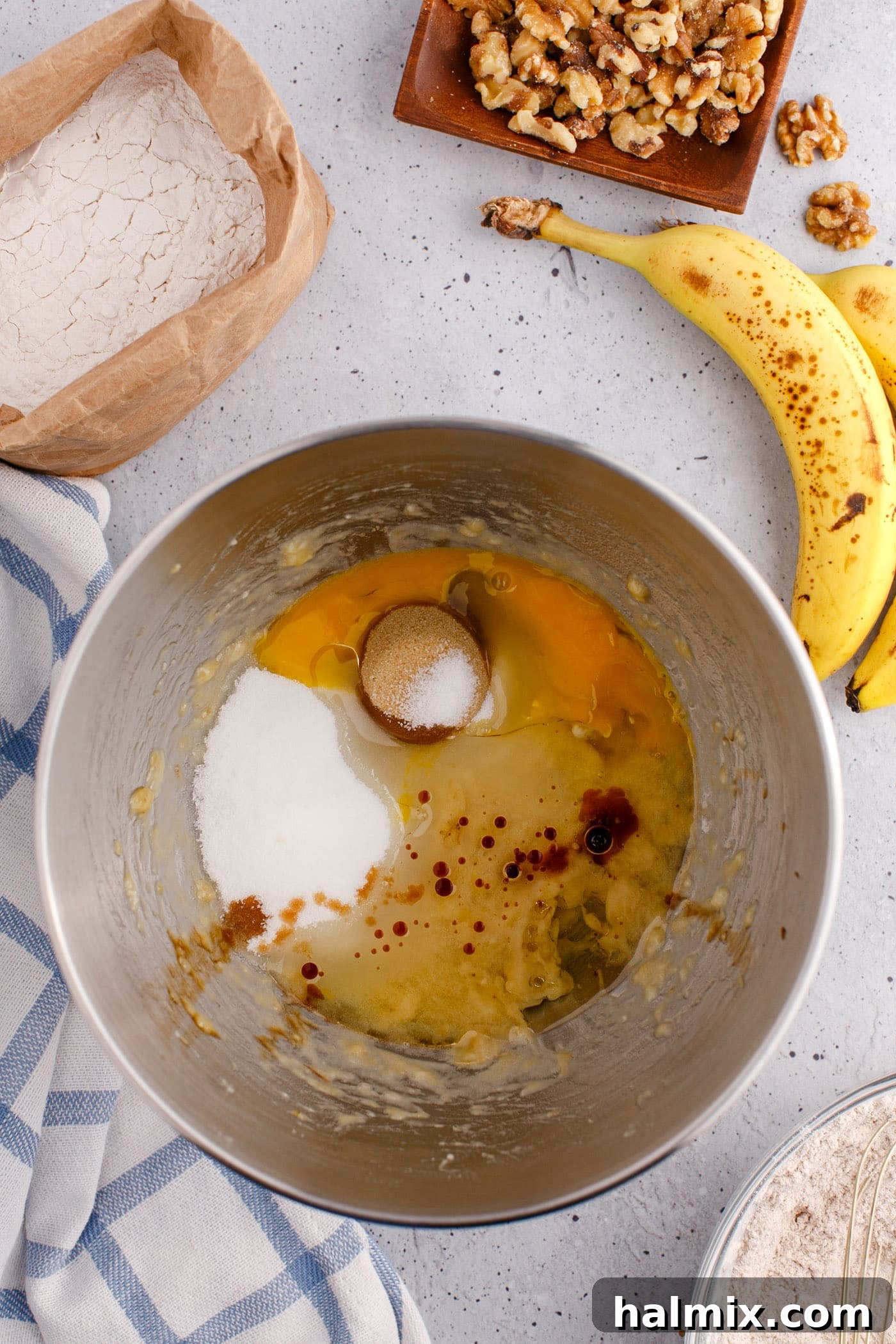 wet ingredients for banana nut bread in a mixing bowl with mashed bananas