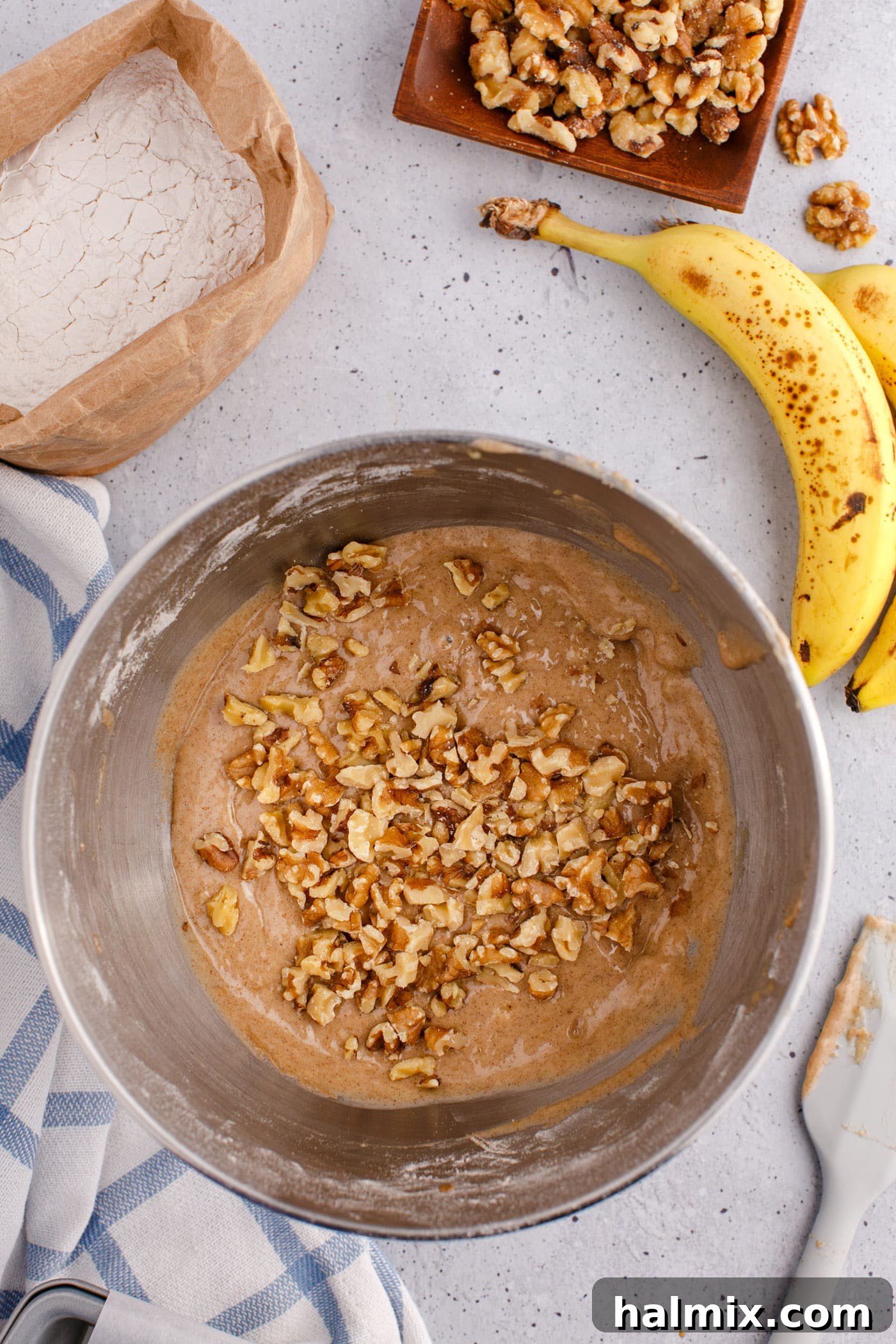 walnuts being folded into banana bread mixture with a rubber spatula