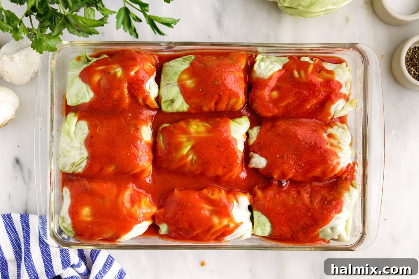 Savory Stuffed Cabbage Bundles 12 Tomato sauce being poured over the top of the cabbage rolls in the baking dish.