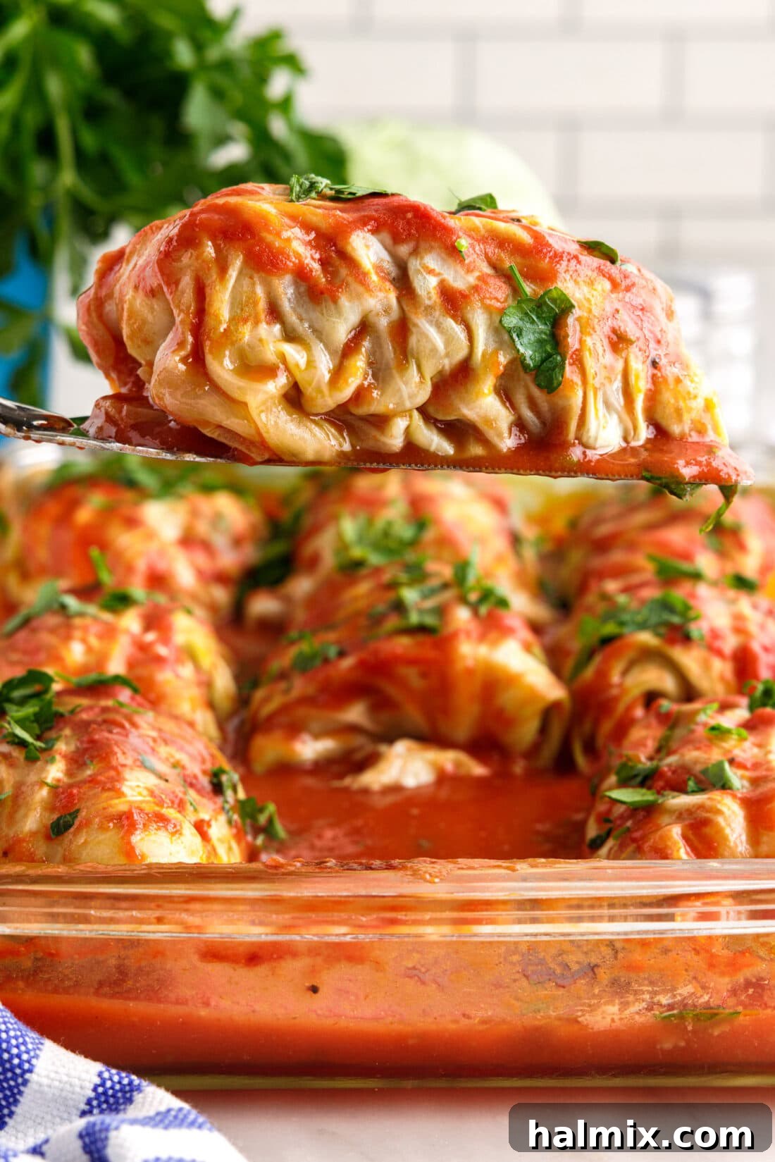 Savory Stuffed Cabbage Bundles 3 A spatula gently lifting a perfectly baked Cabbage Roll from the casserole dish, revealing its rich tomato sauce coating.