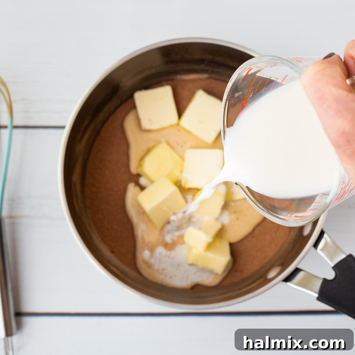 pouring milk into saucepan with butter and cocoa powder