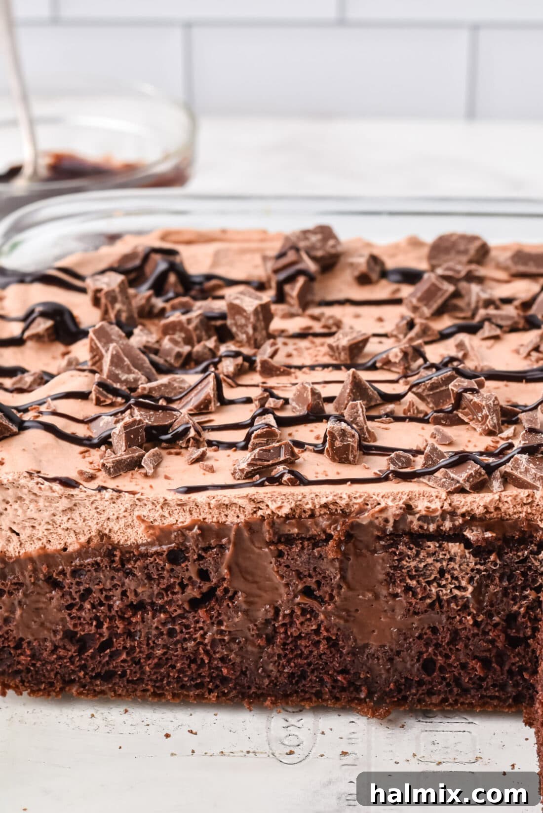 An overhead view of a freshly baked Triple Chocolate Poke Cake in a baking pan, showing the small holes poked into the surface, ready for the pudding infusion.