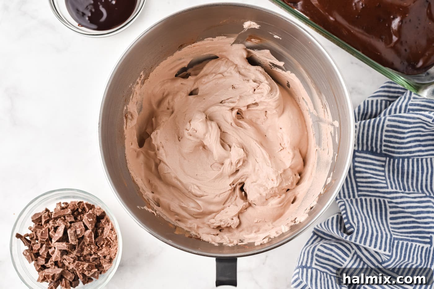 Homemade chocolate whipped topping, fluffy and light, in a large mixing bowl with an electric mixer's whisk attachment.