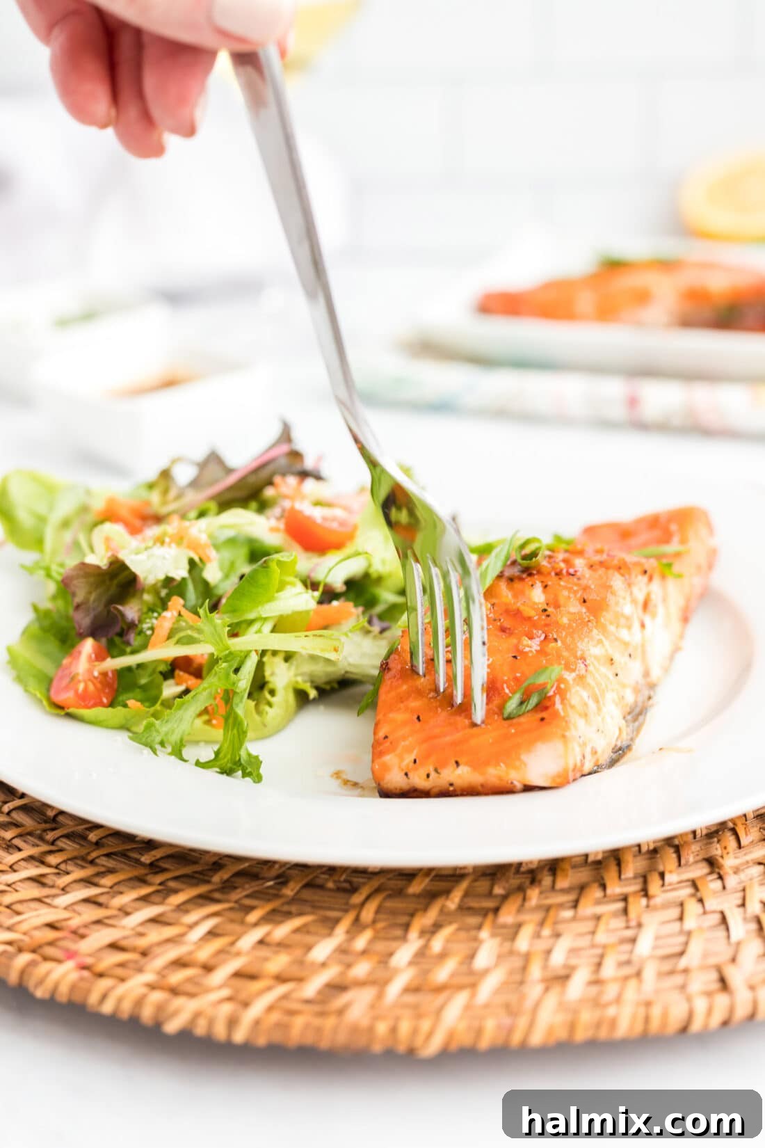 Maple Soy Glazed Salmon 3 A fork piercing into a flaky piece of pan-seared Maple Soy Salmon on a white plate.