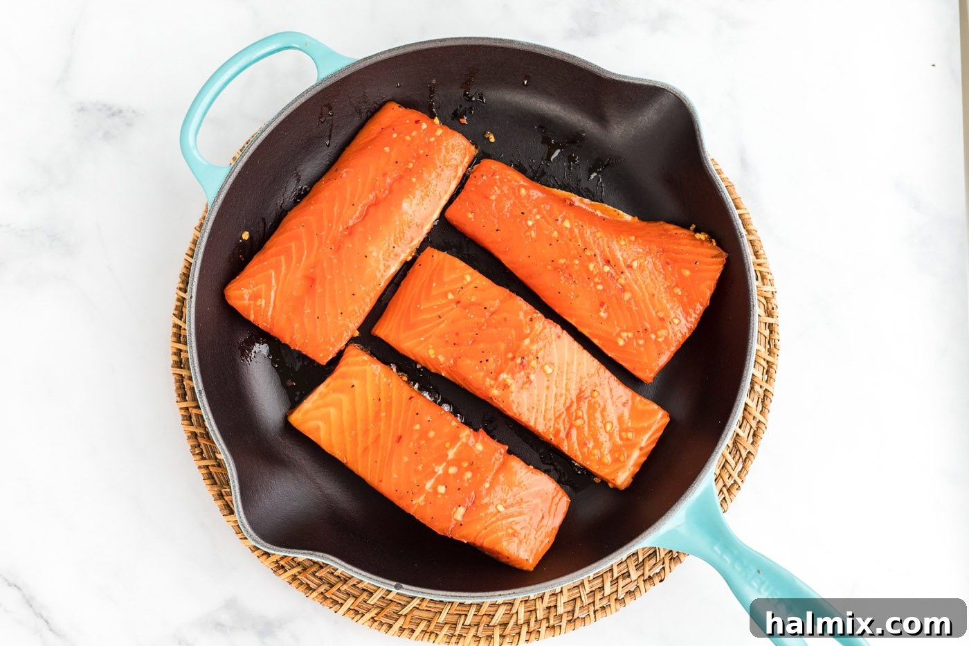 Salmon fillets searing in an oven-proof skillet.