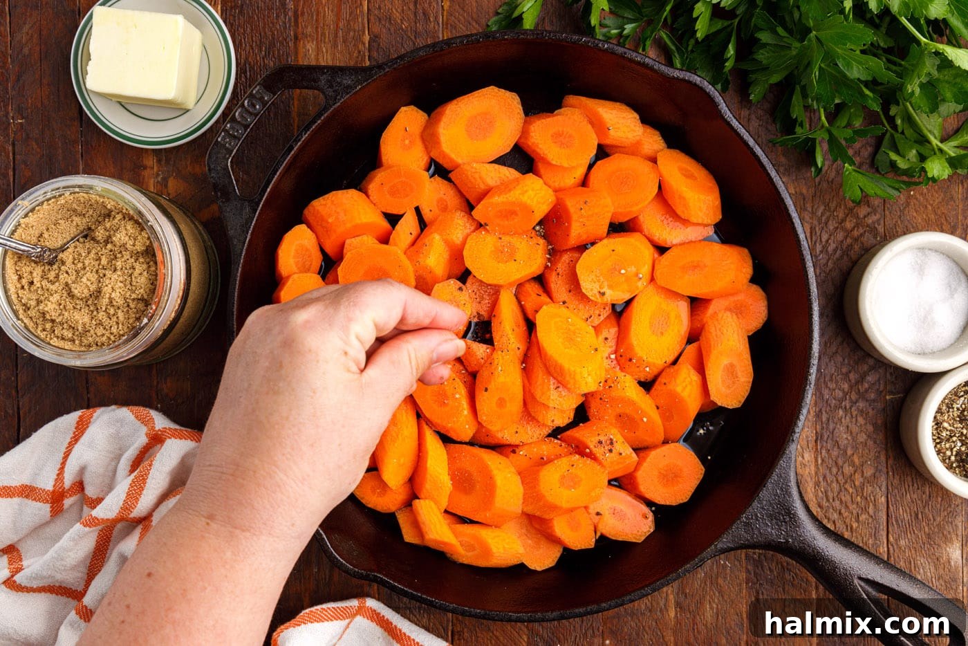 adding salt and pepper to skillet with sliced carrots