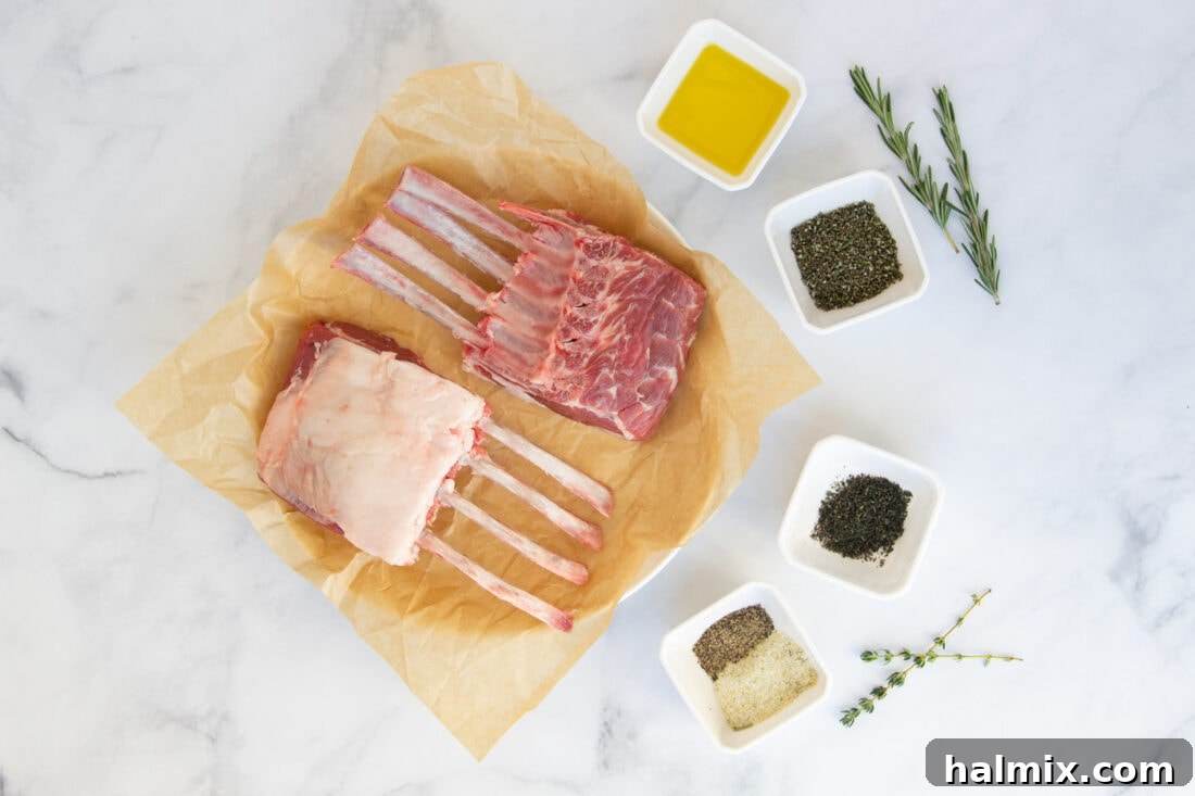 A selection of fresh ingredients including a rack of lamb, rosemary, thyme, garlic salt, black pepper, and olive oil laid out on a cutting board.