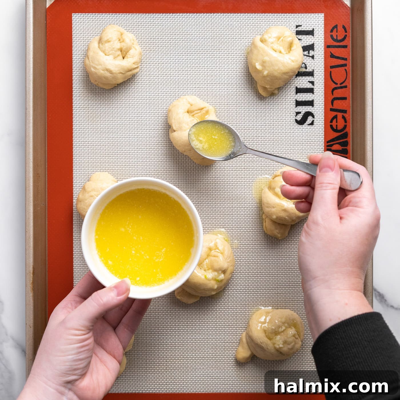 spooning garlic butter over dough knots