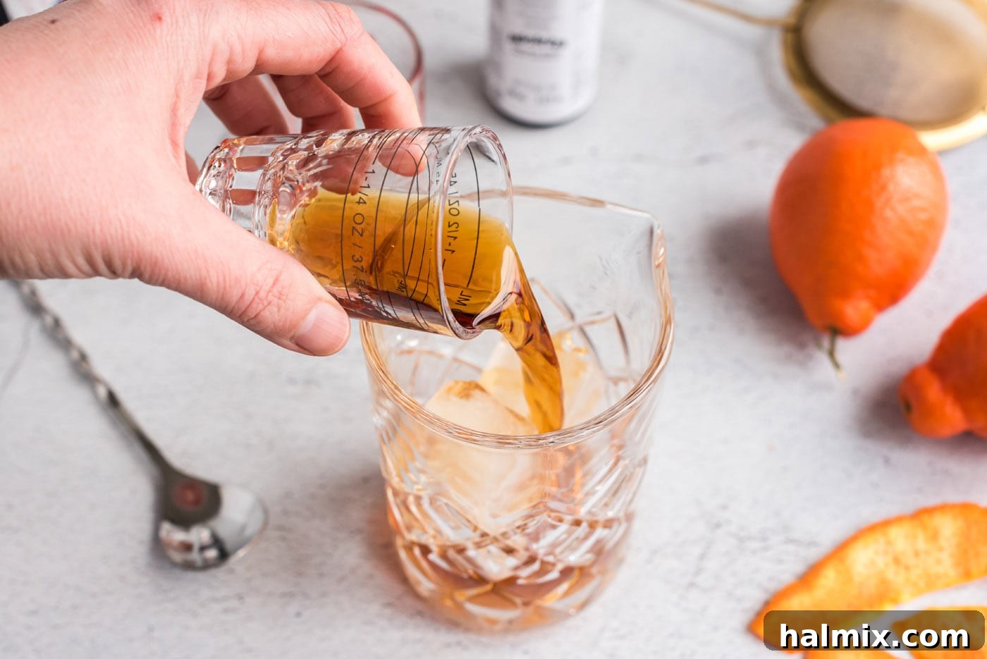 pouring whiskey and vermouth into mixing glass
