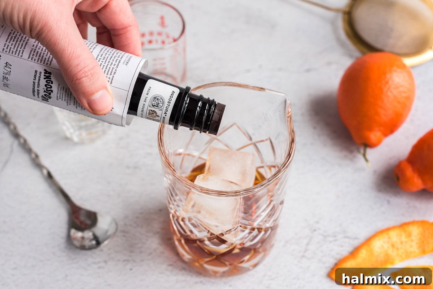 adding bitters to manhattan cocktail mixing glass