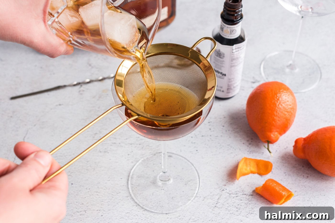 straining manhattan cocktail into a coupe glass