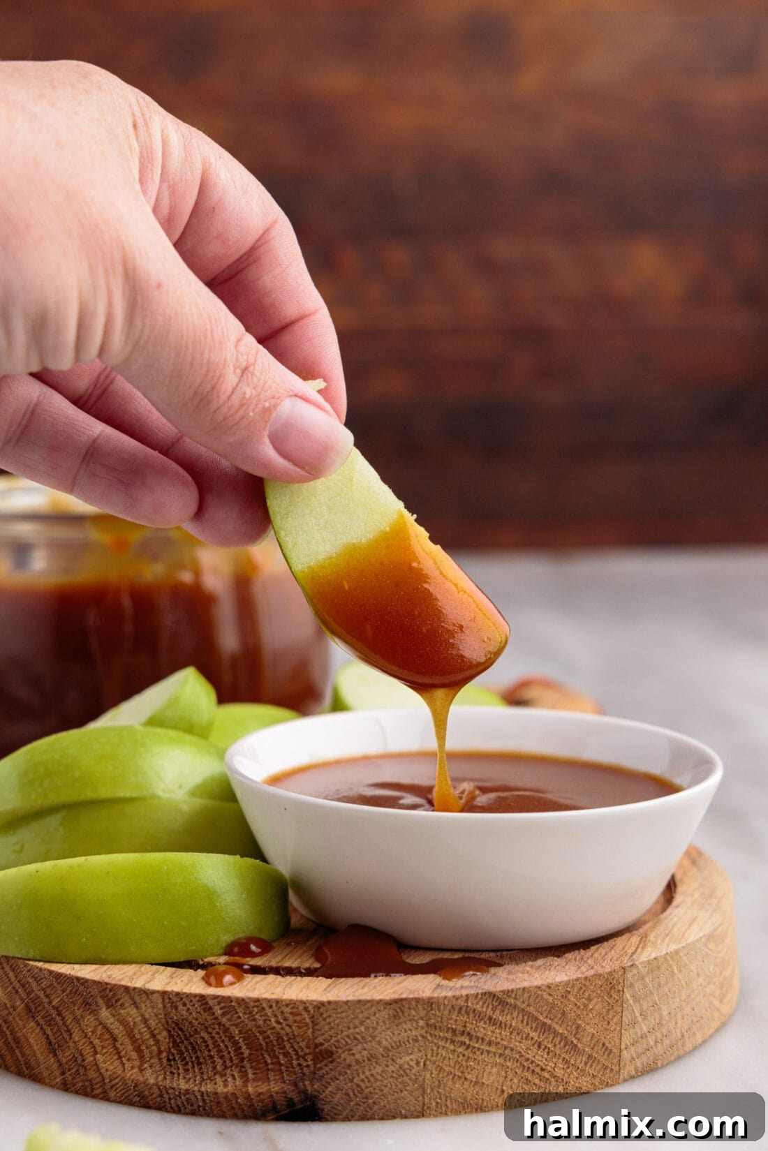 dipping apple slice into Caramel Sauce