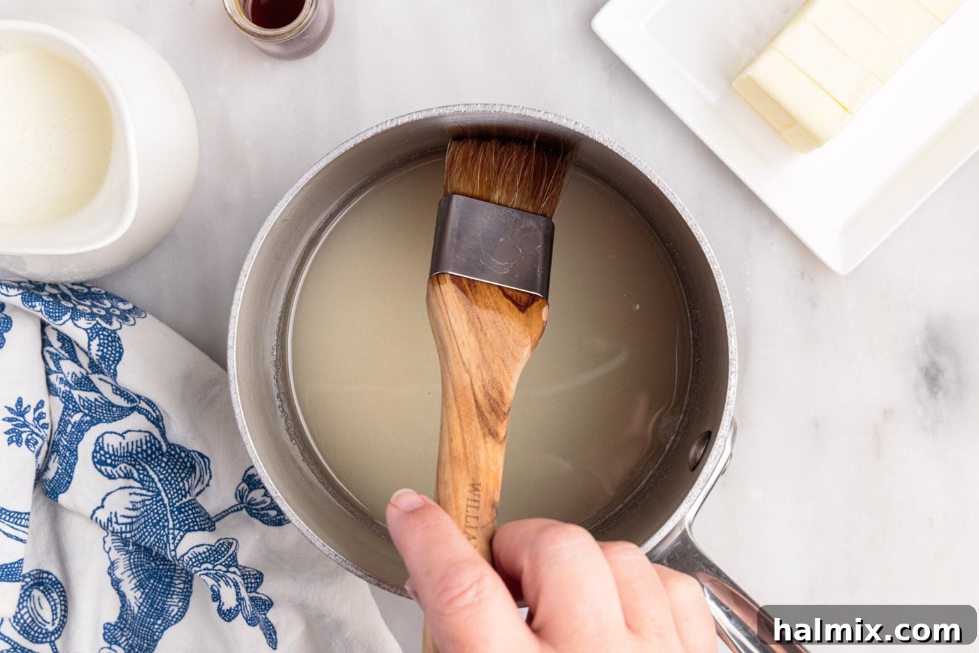 wiping down side of saucepan with a pastry brush