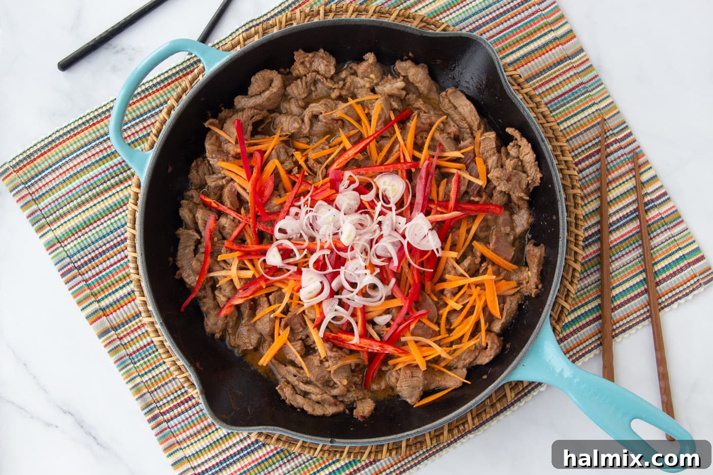 shallots, peppers, and carrots over beef in a skillet
