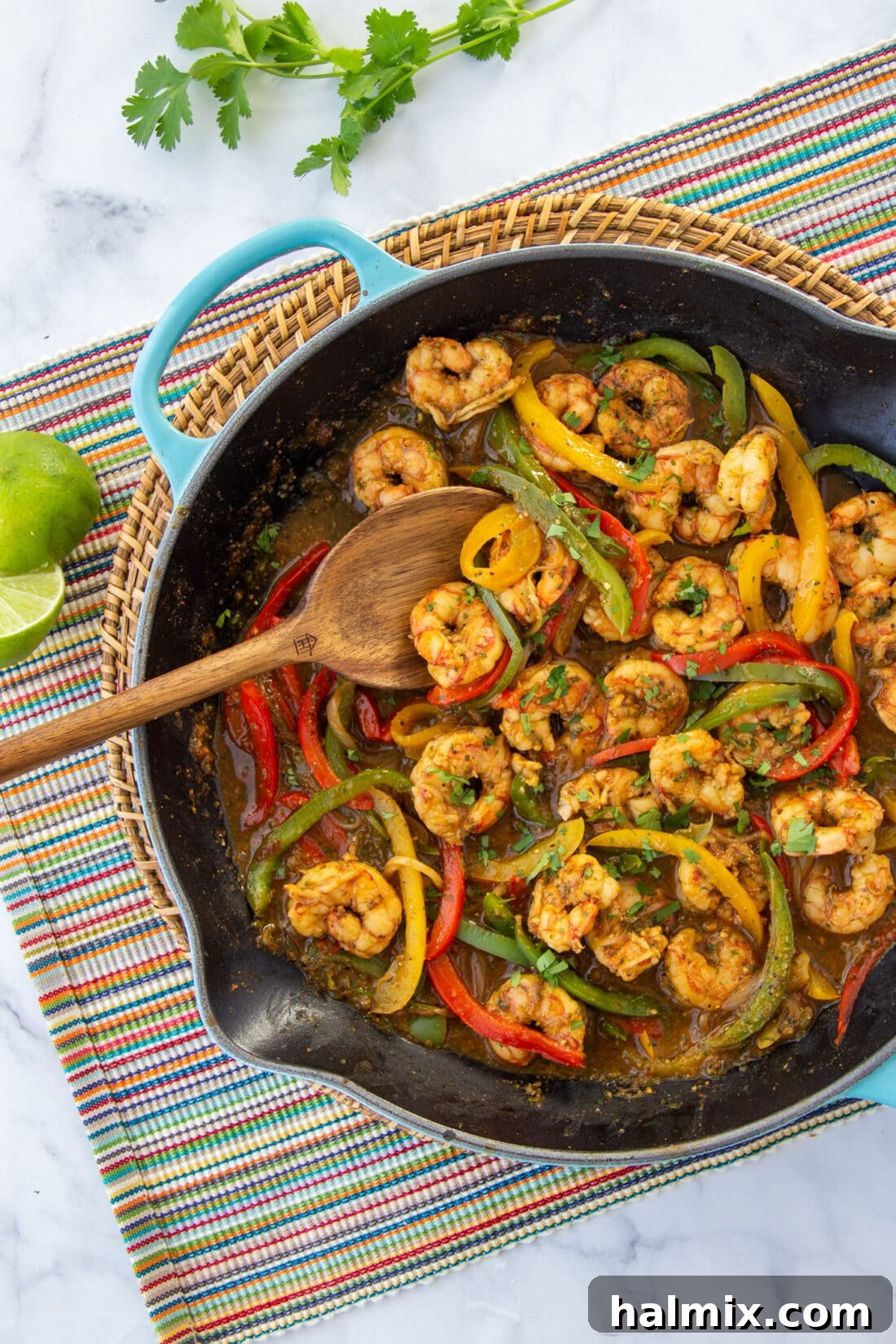 Sizzling Shrimp Fajitas in a cast iron skillet, garnished with fresh cilantro and lime wedges