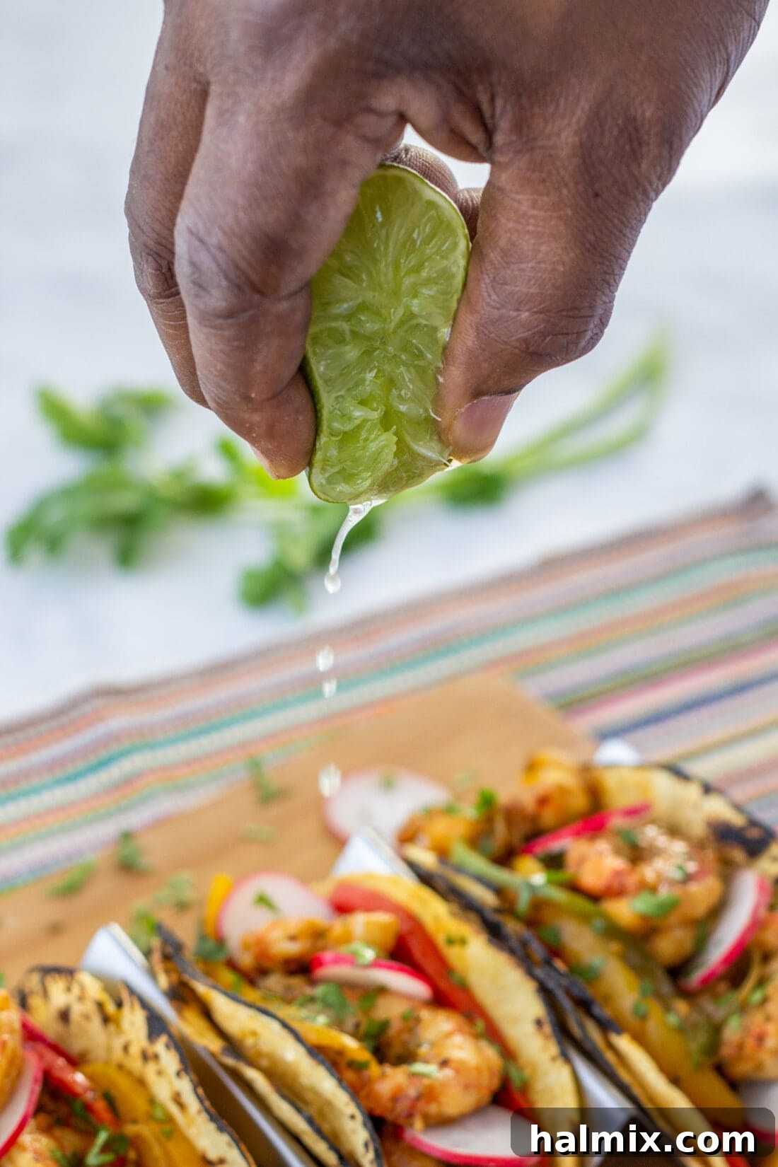 Fresh lime being squeezed over a plate of Shrimp Fajitas for added zest