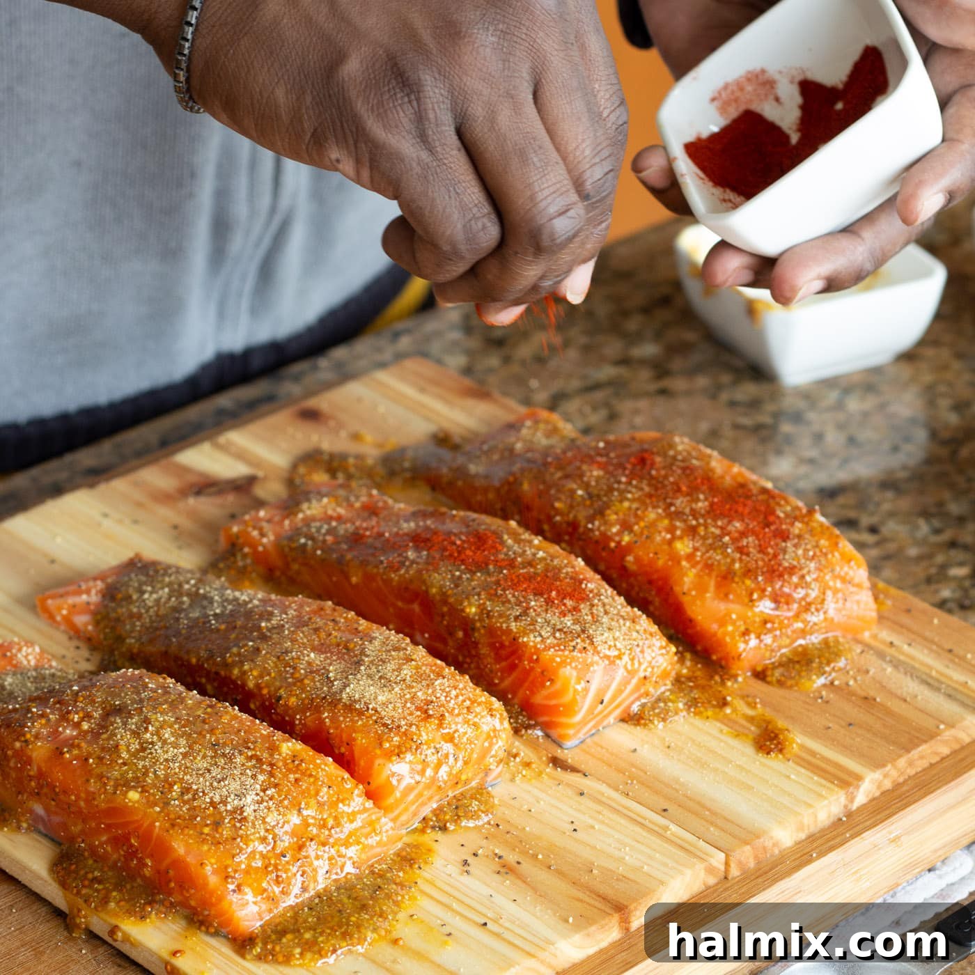 Sprinkling smoked paprika and brown sugar over the glazed salmon fillets.