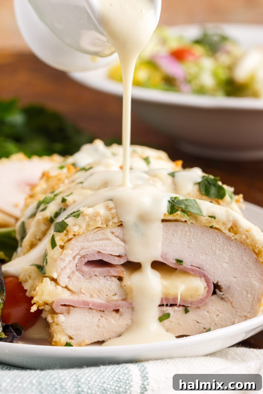 drizzling sauce on Chicken Cordon Bleu
