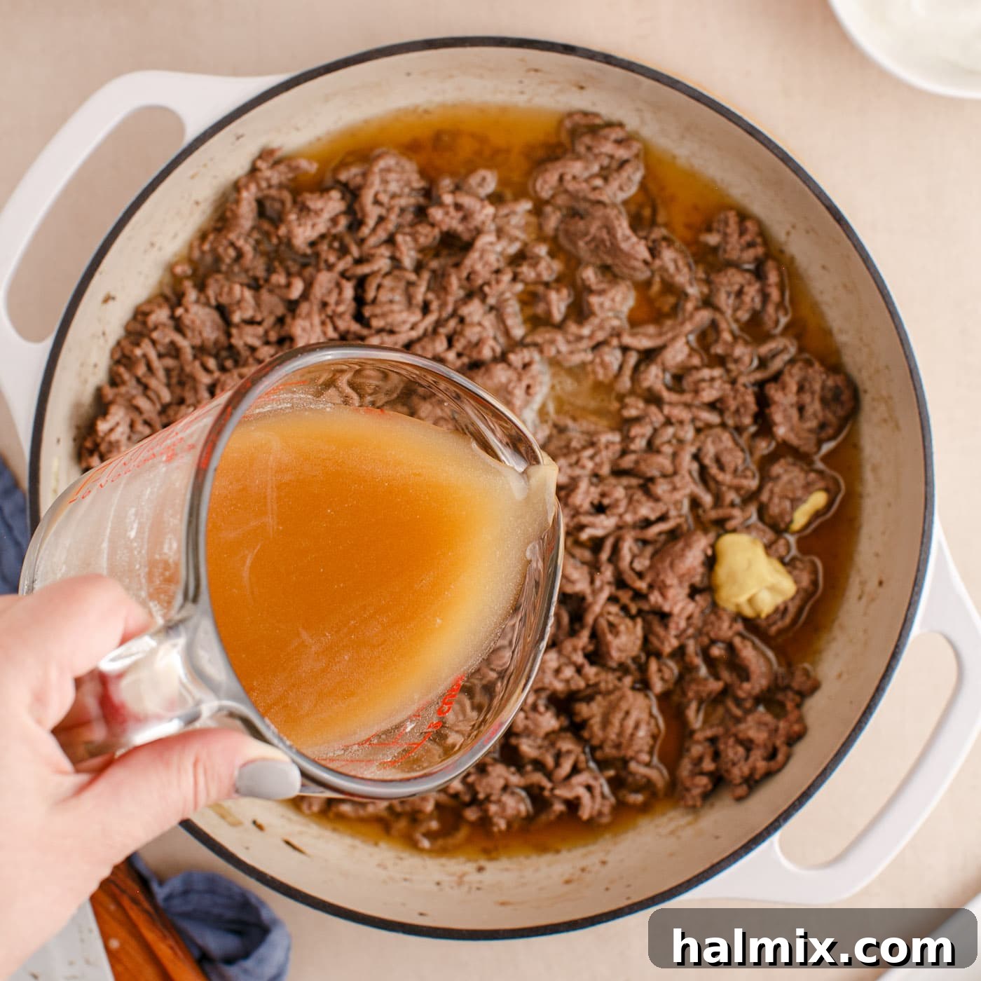 Creamy Ground Beef Stroganoff 8 Adding a mixture of beef broth and flour to the ground beef in the skillet to thicken the sauce.