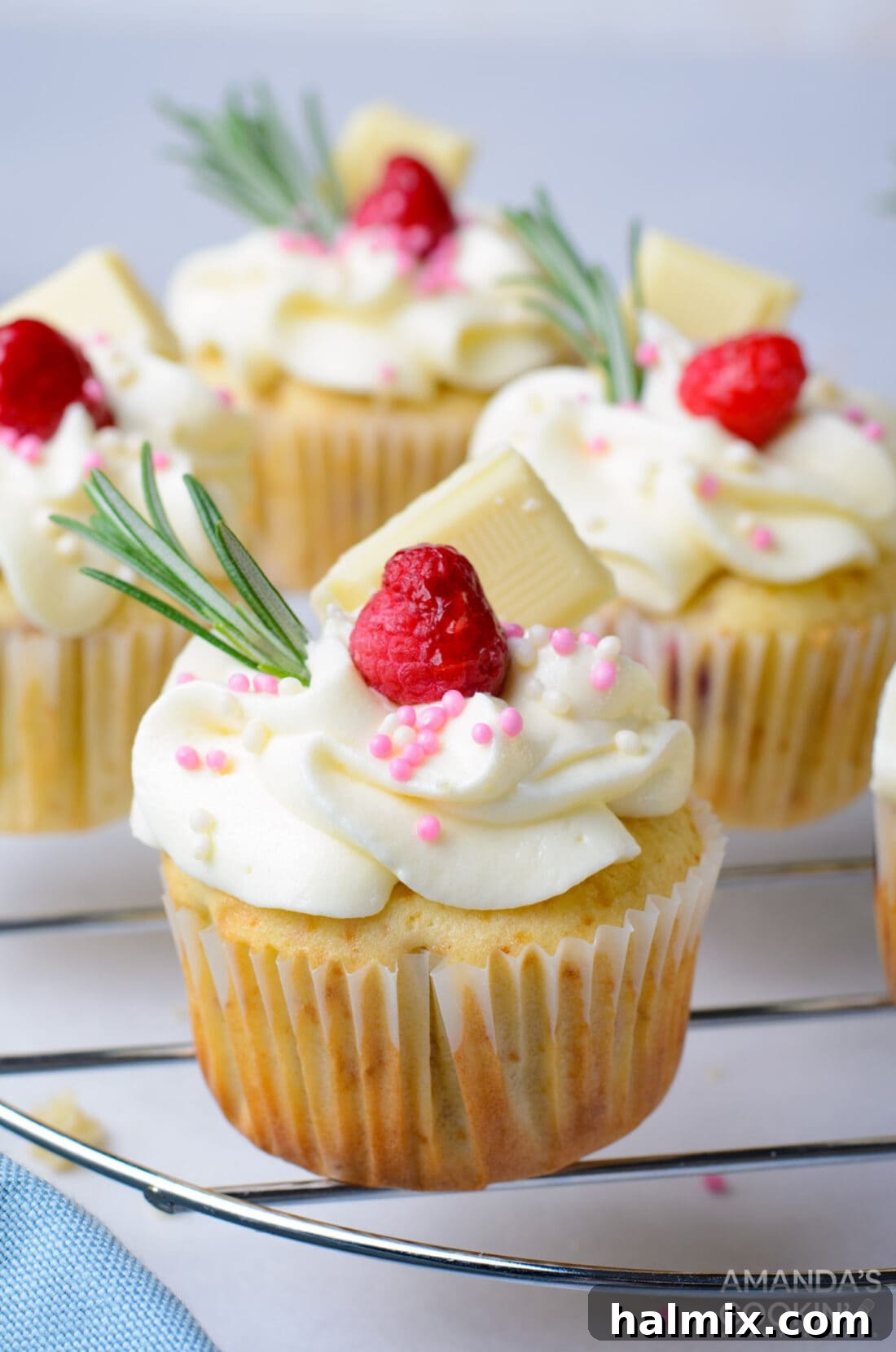 Soft and fluffy Raspberry White Chocolate Cupcakes with white chocolate buttercream and raspberry jam filling arranged on a cooling rack