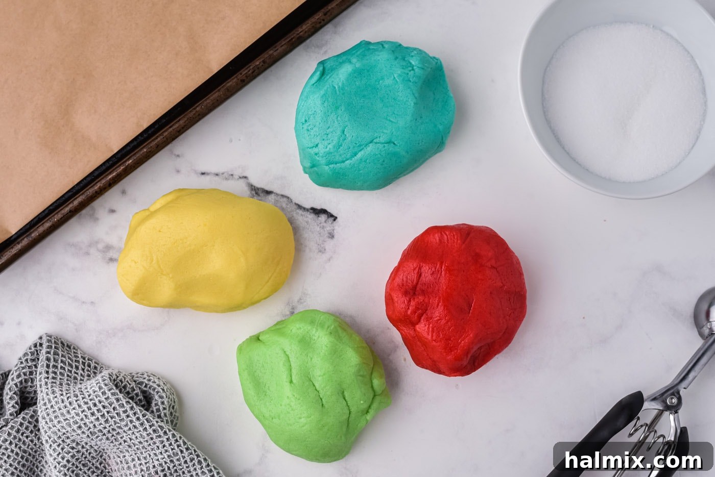 four different colored jello cookie dough balls, ready for baking