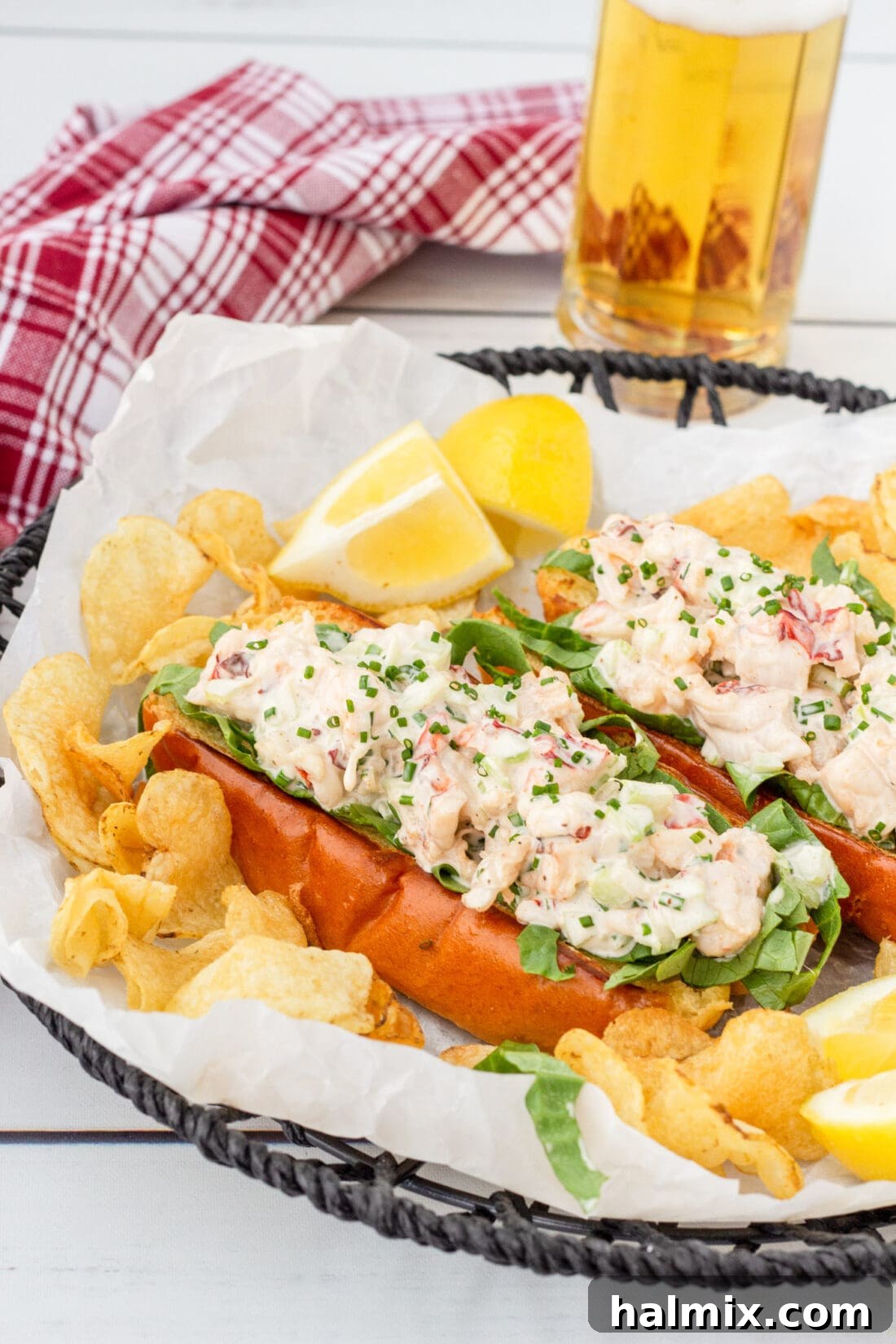 Three perfectly assembled lobster rolls served in a rustic basket with golden potato chips