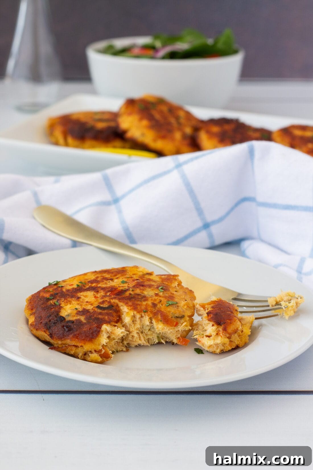 A single smoked salmon fish cake with a forkful removed, showcasing the tender, flaky interior.