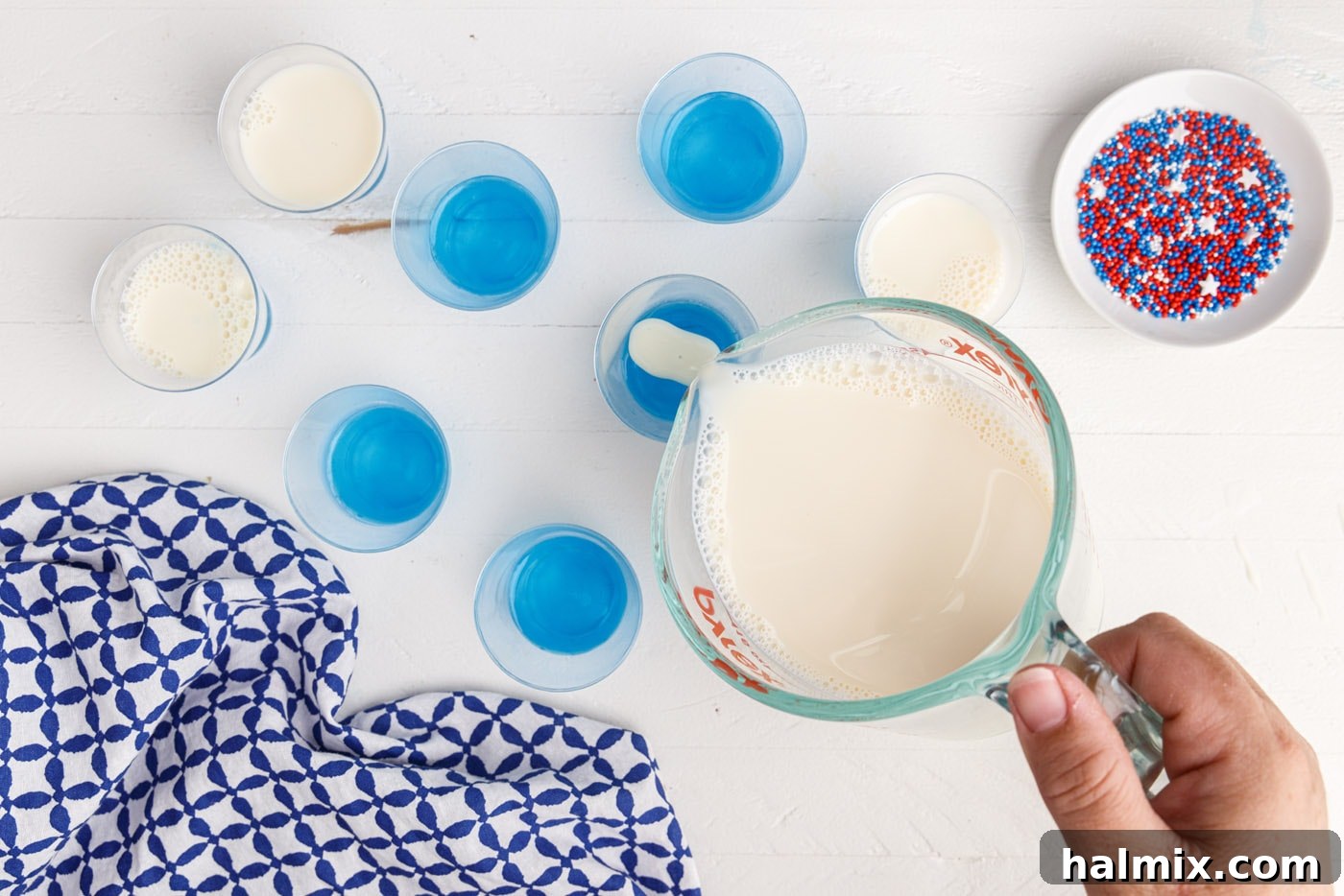 pouring sweetened condensed milk jelly on top of blue jello