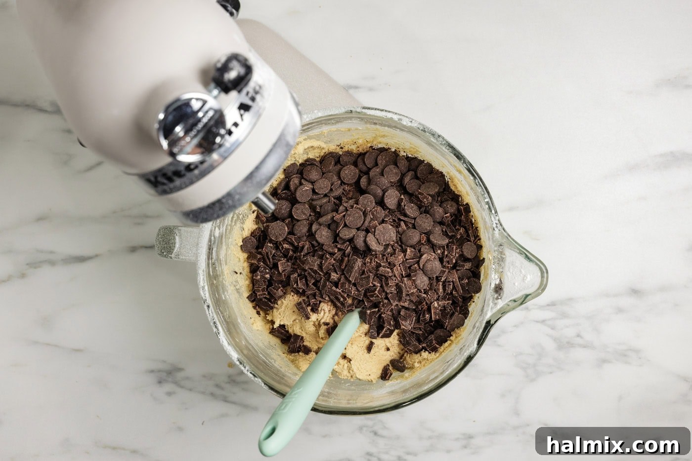 Chocolate chips and chopped chocolate being added to the cookie dough batter