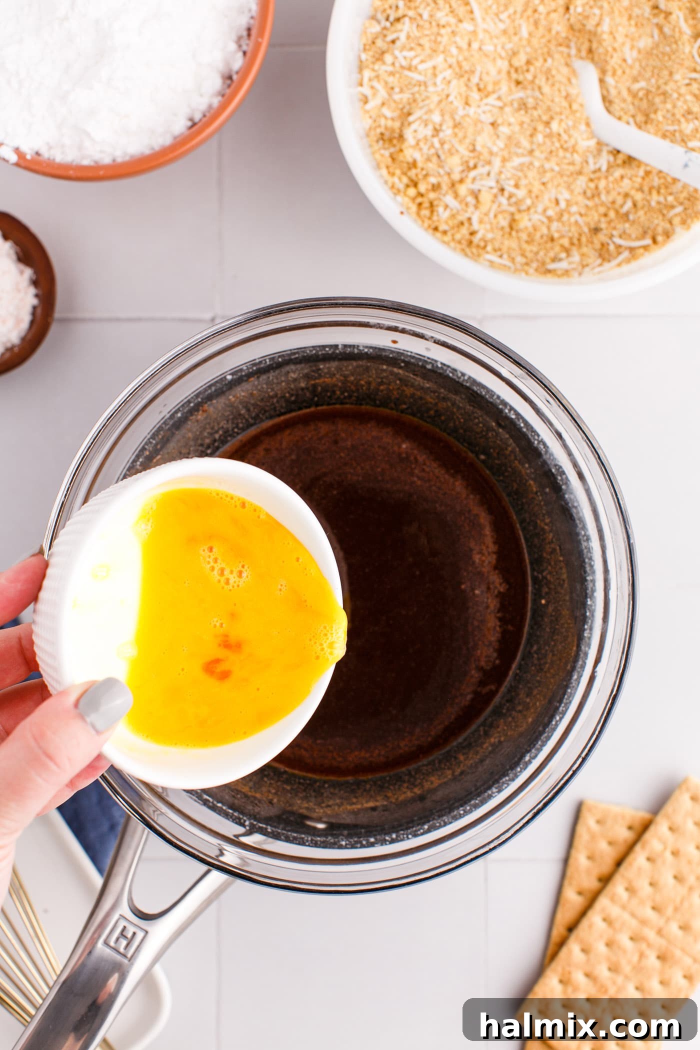 Adding beaten egg to the warm cocoa and butter mixture while whisking.