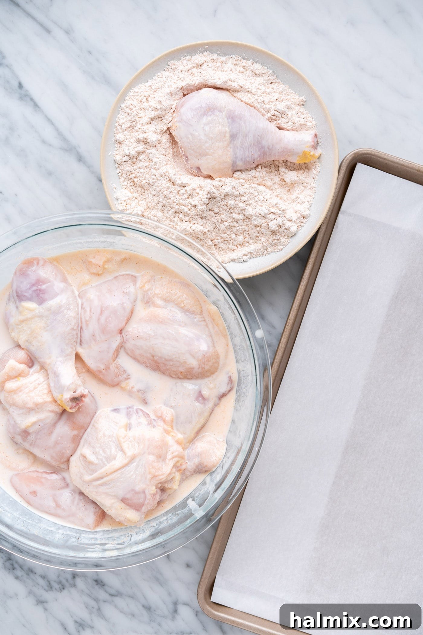 A chicken piece being dredged in the seasoned flour mixture, showing a thick, even coating being applied by hand, ensuring full coverage.