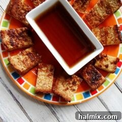 Close-up of golden brown French toast sticks on a plate with syrup.