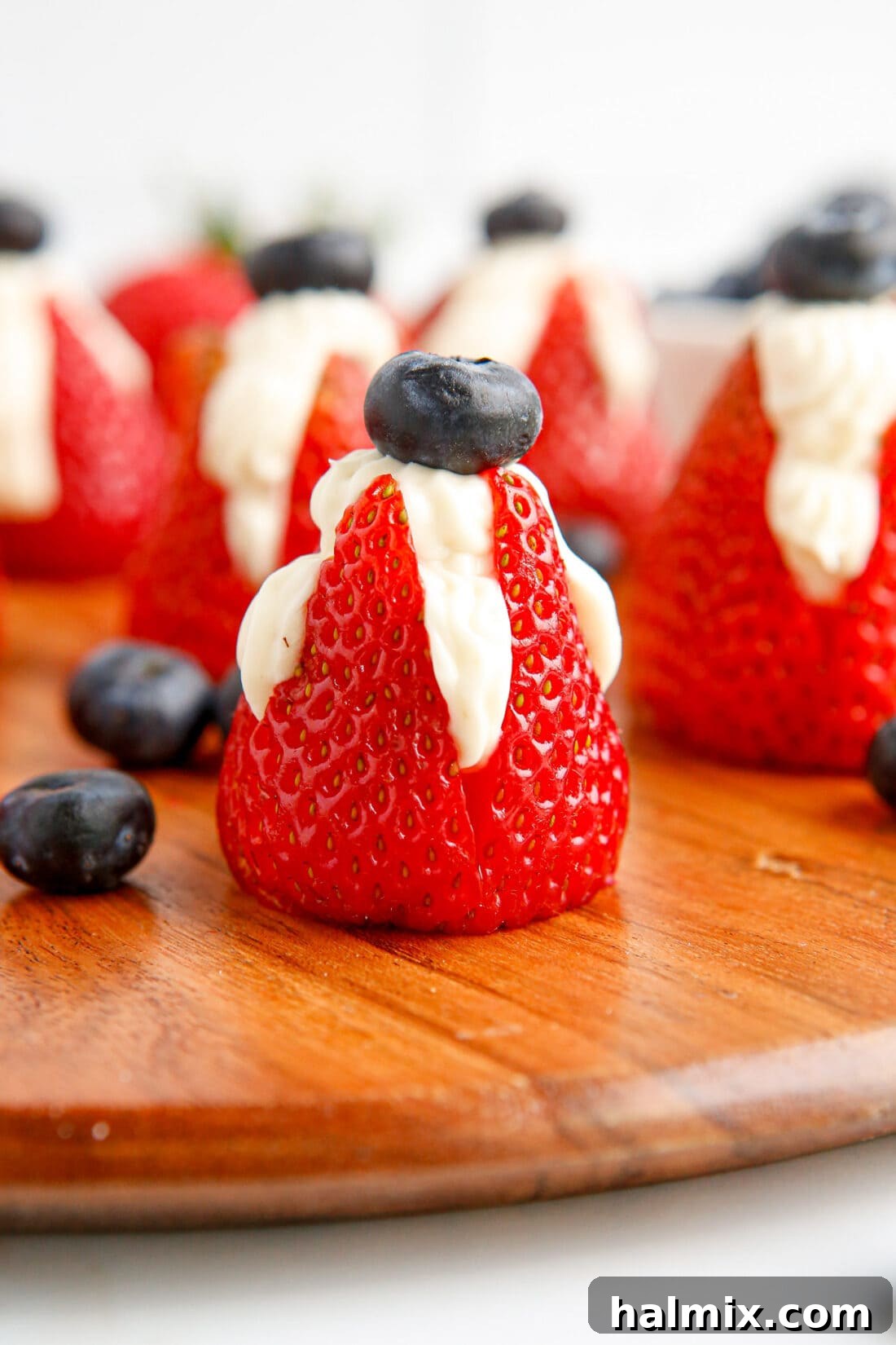 Cheesecake Stuffed Strawberries with a blueberry on top, a perfect no-bake dessert.