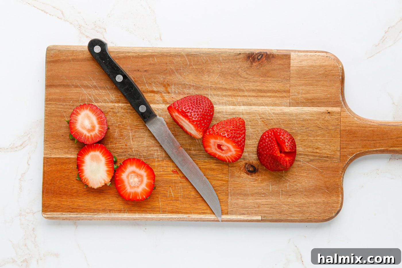 Slicing the top off of strawberries to create a flat base for stuffing.