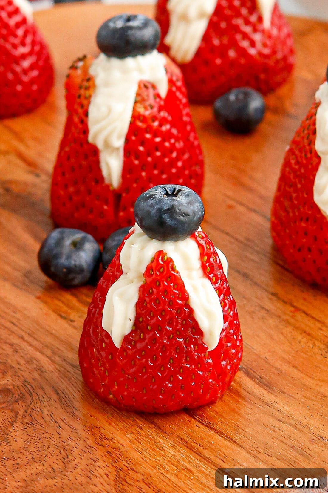 Patriotic themed Stuffed Strawberries, garnished with blueberries, on a white plate.