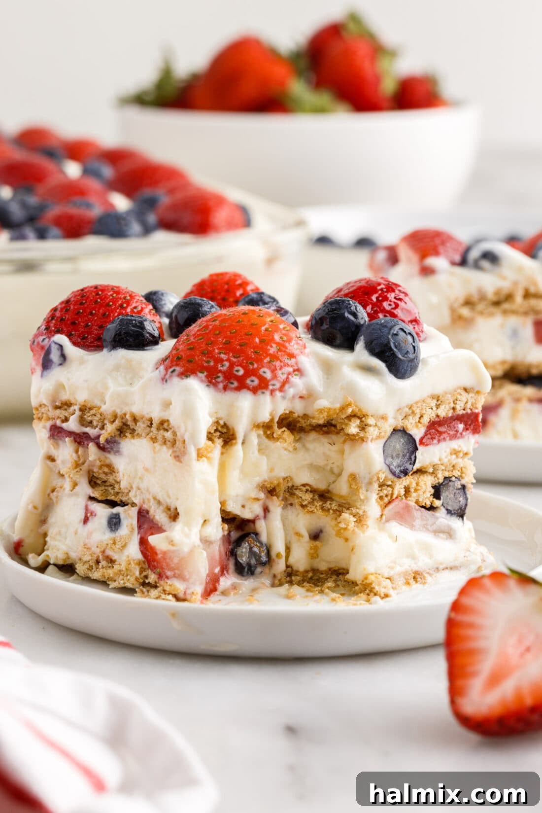 A delectable slice of Mixed Berry Icebox Cake with a spoonful taken out, showcasing its vibrant layers and creamy texture.