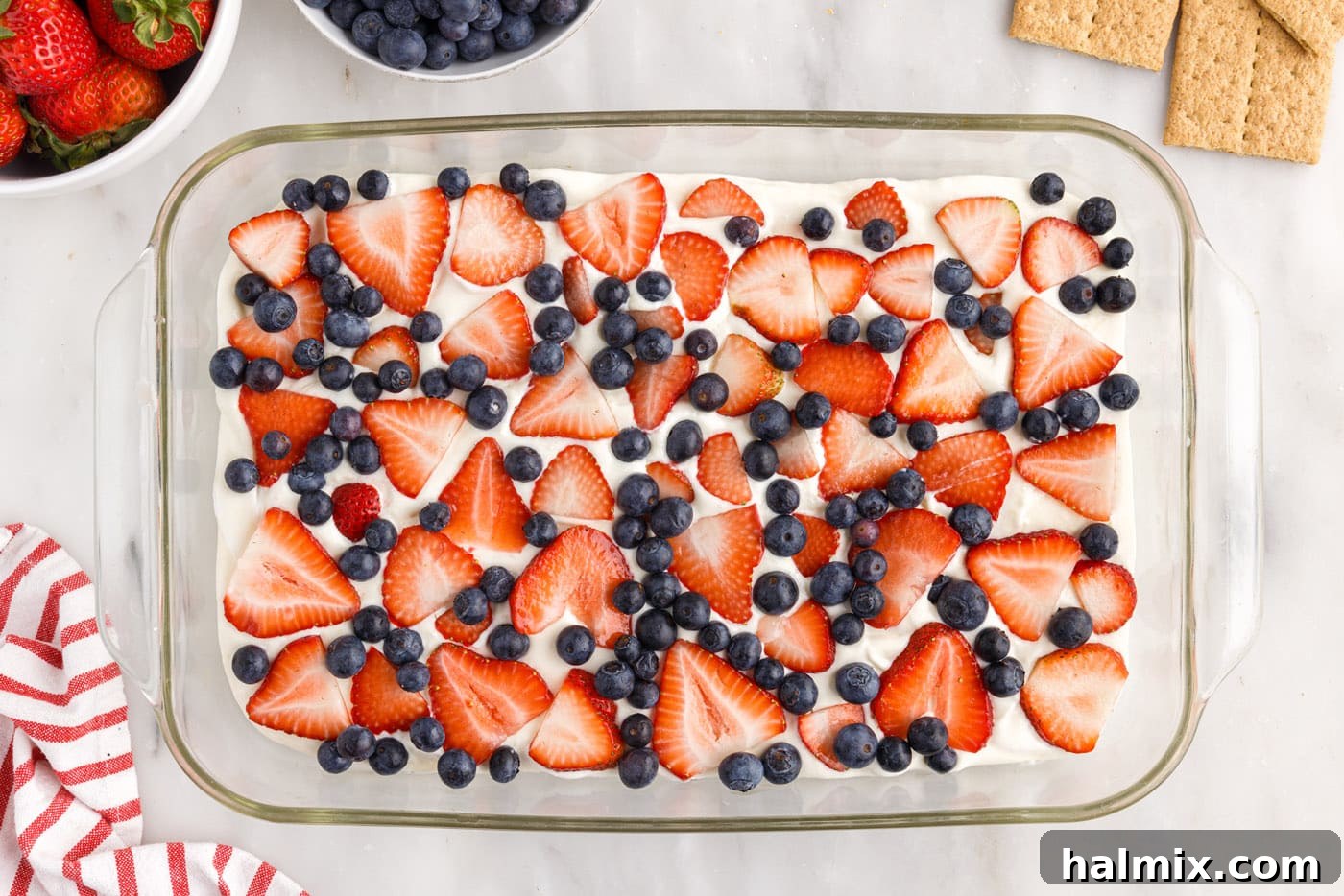 A vibrant layer of sliced strawberries and whole blueberries arranged over the cream cheese pudding mixture.
