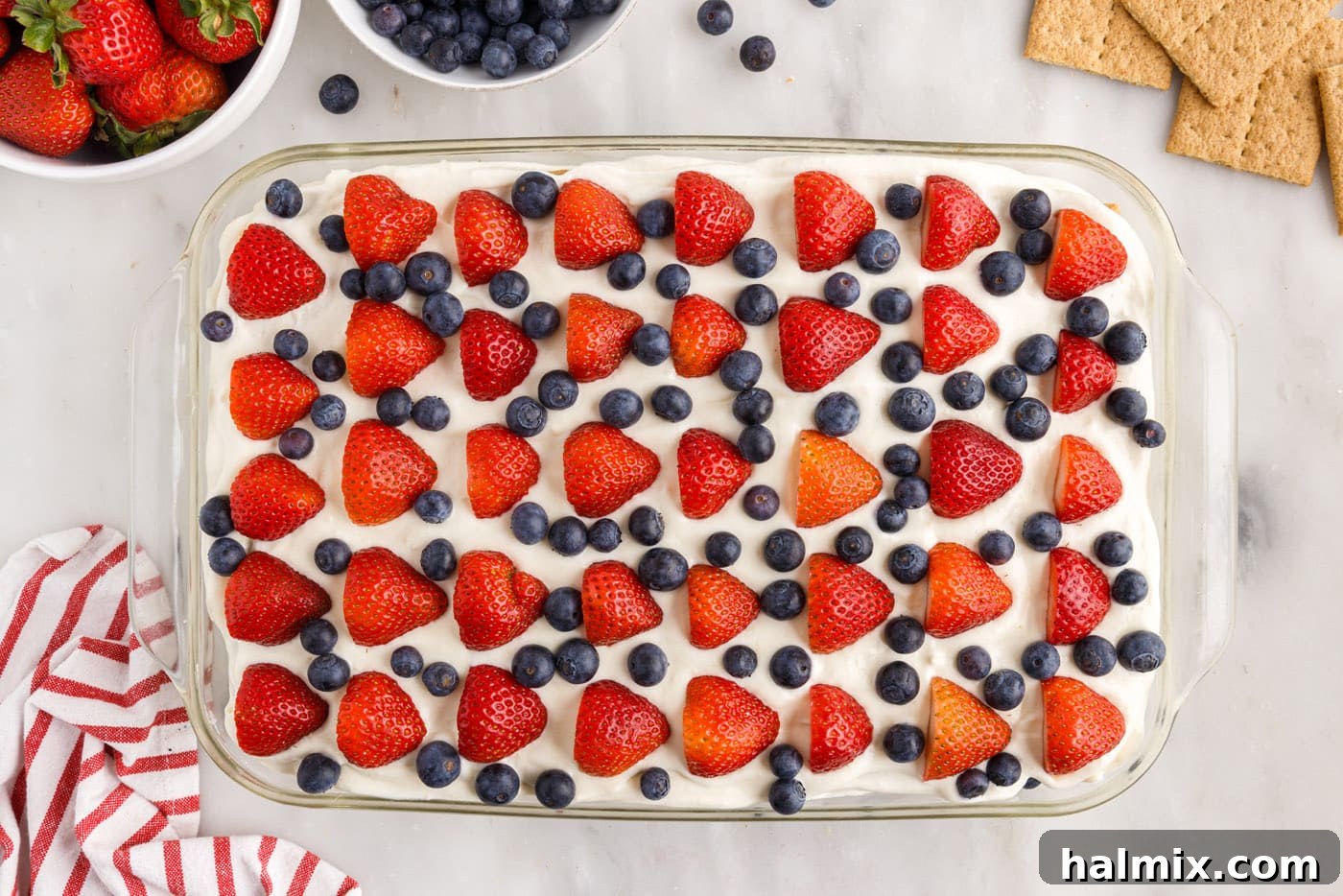 Fresh strawberries (halved) and blueberries arranged decoratively on top of the finished icebox cake.