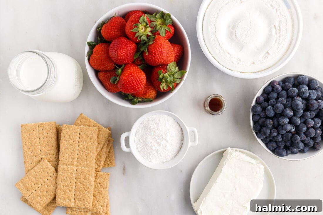 A display of all the fresh ingredients needed for Mixed Berry Icebox Cake, including fresh strawberries, blueberries, graham crackers, milk, cream cheese, and Cool Whip.
