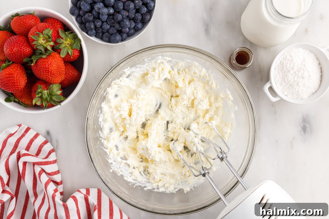Cream cheese being beaten in a bowl with an electric mixer until light and fluffy.