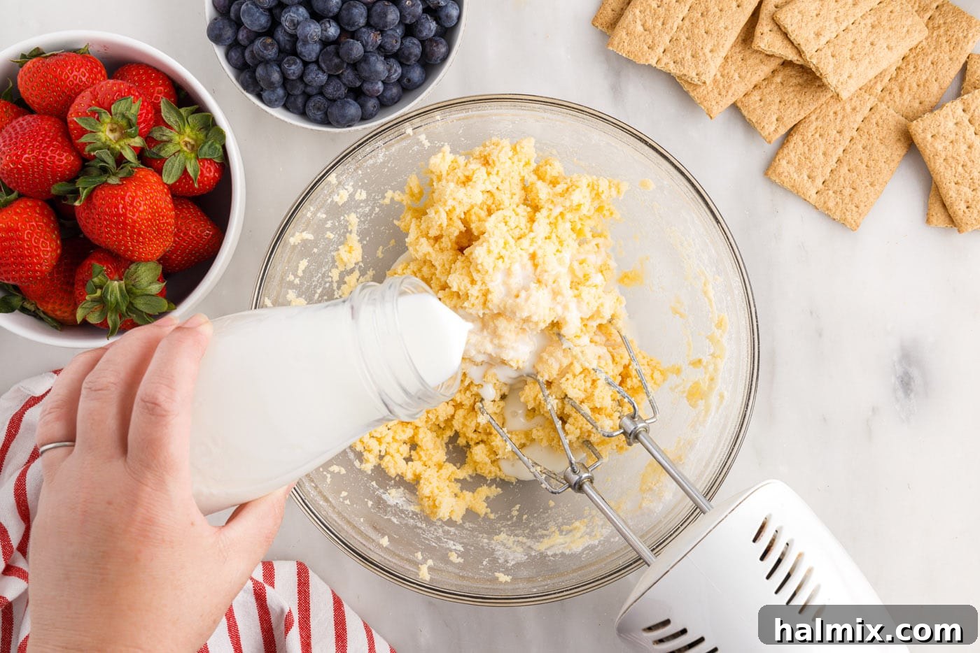 Adding milk to the cream cheese mixture while beating, ensuring a smooth blend.