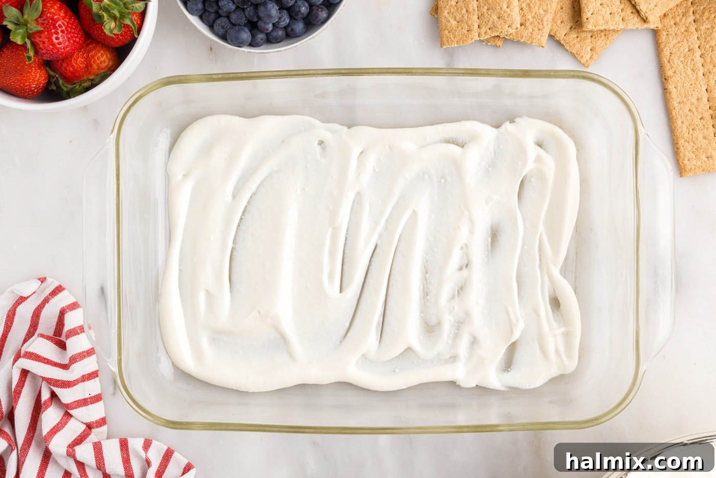 A thin layer of cool whip pudding mixture spread evenly across the bottom of a 9x13 baking dish.