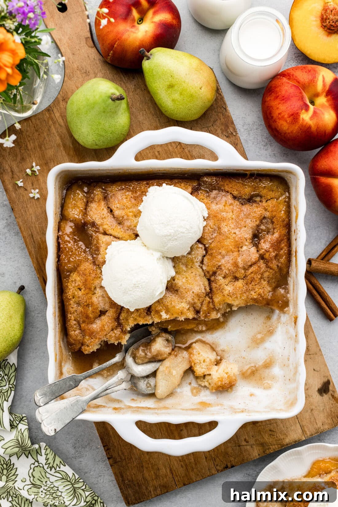 Baking dish of Pear-Peach Cobbler topped with two scoops of ice cream