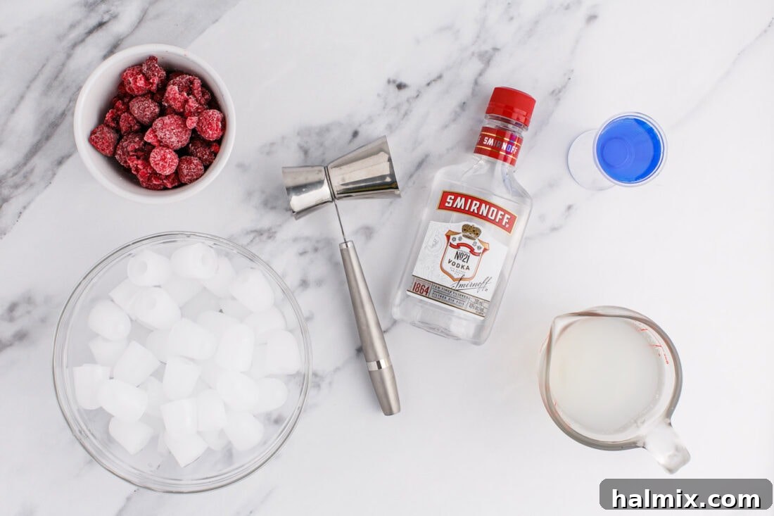 Freedom's Frosty Vodka Lemonade 4 Patriotic Vodka Lemonade Slushie ingredients laid out on a table, including frozen raspberries, lemonade, vodka, blue curacao, and ice.