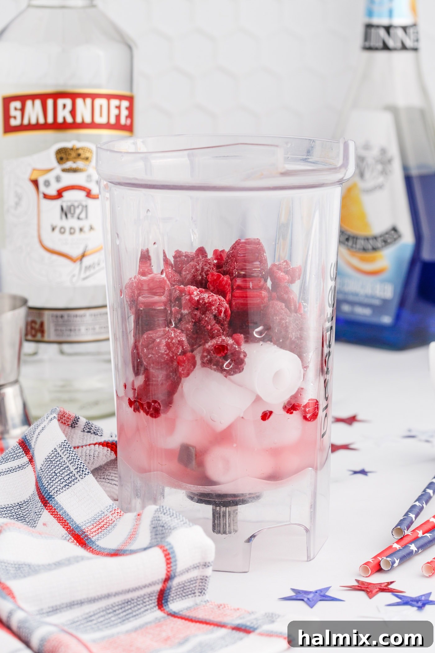 Freedom's Frosty Vodka Lemonade 5 Raspberry, lemonade, ice, and vodka in a blender being prepared for the red layer of the slushie.