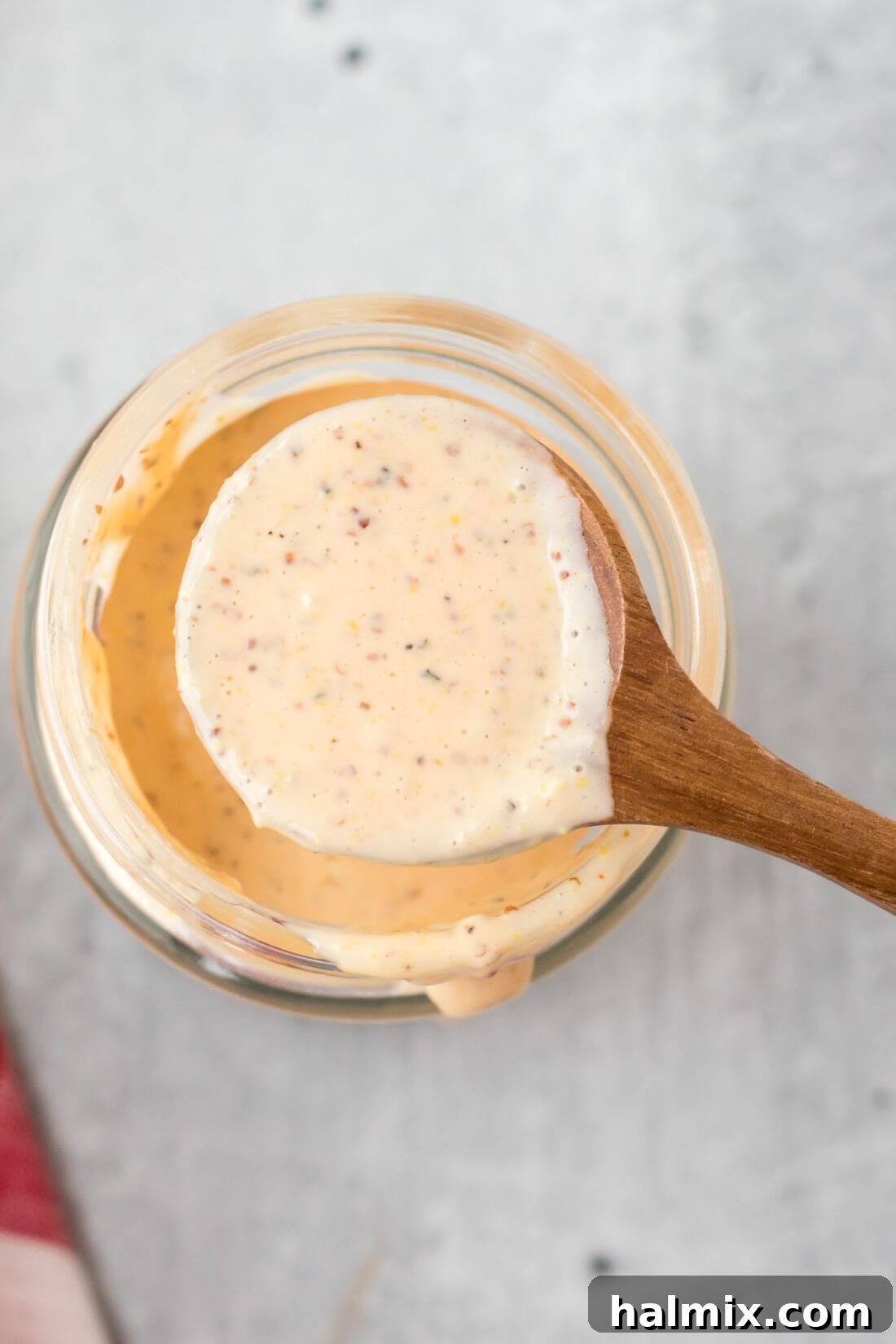Overhead photo of a spoon coated in Alabama White Sauce, ready for tasting.