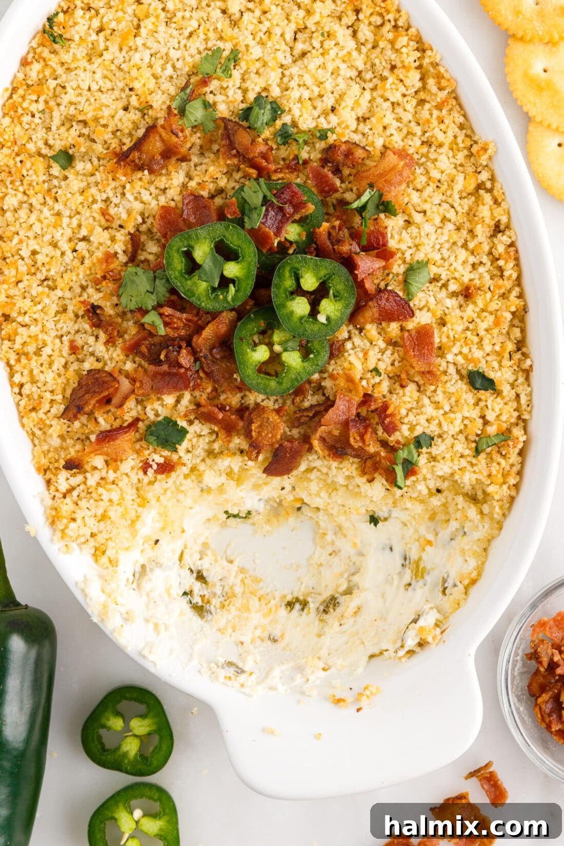 Baked Jalapeno Popper Dip in a baking dish with some portions removed by dippers