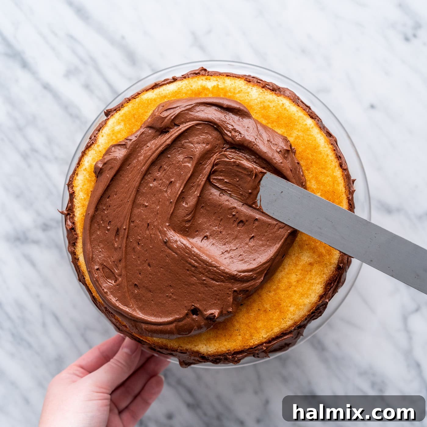 Swirled Delight 15 using a spatula to spread chocolate frosting evenly over the top of the marble cake