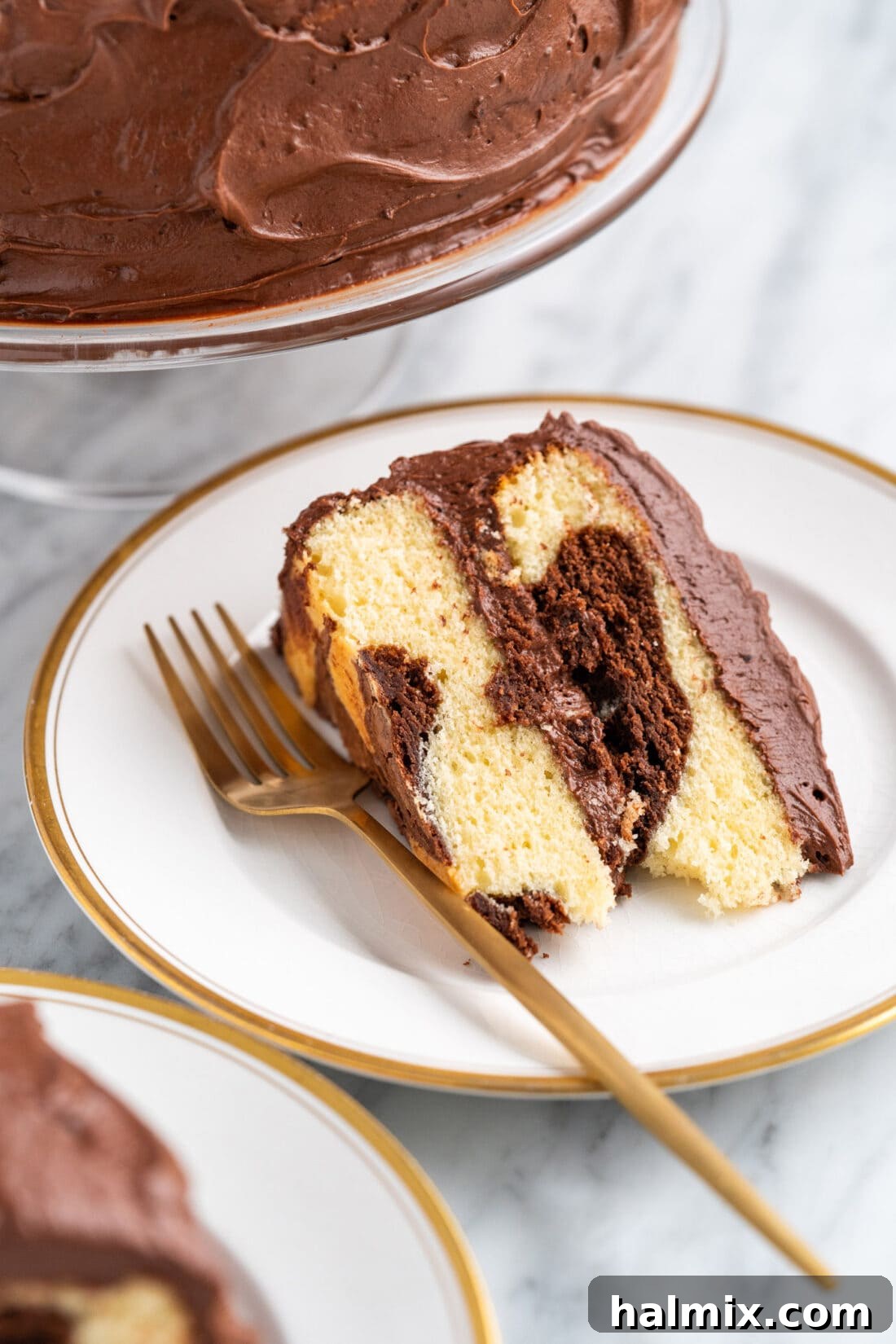 Swirled Delight 16 Marble Cake slice on a white plate with a fork, ready to be enjoyed